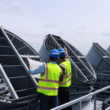 Construction team assessing large rooftop fans